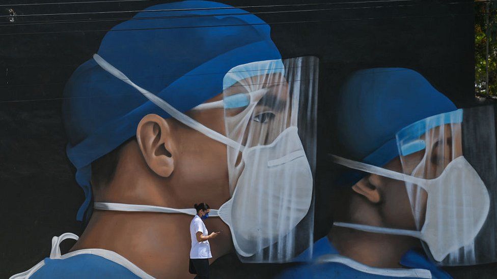 man walking past mural of medical workers wearing PPE