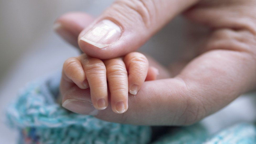 Mother holding newborn's hand