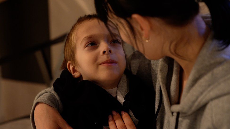 A young boy with cancer gazes at his mum
