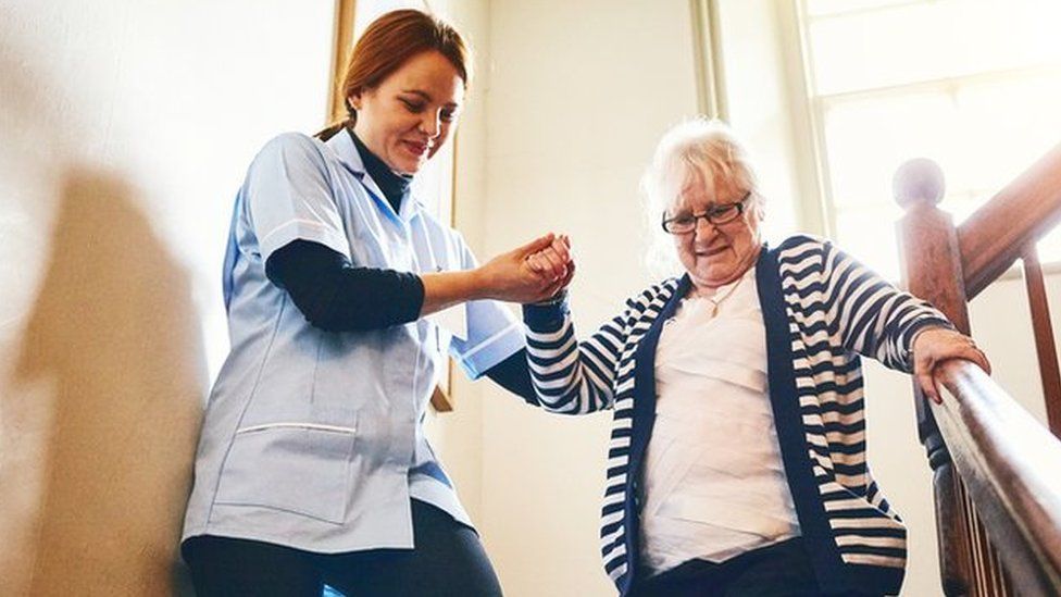 A care worker helping a woman downstairs