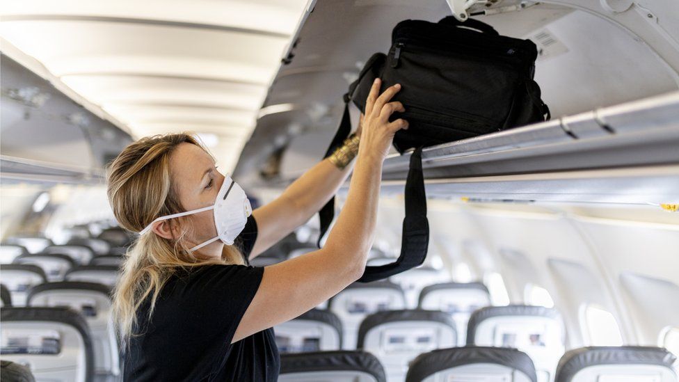 Stock pic of a woman on a plane in a mask