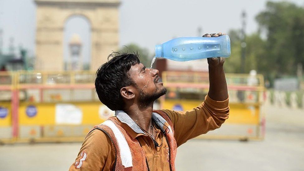 A worker pours water amid the scorching heat near India Gate in Delhi