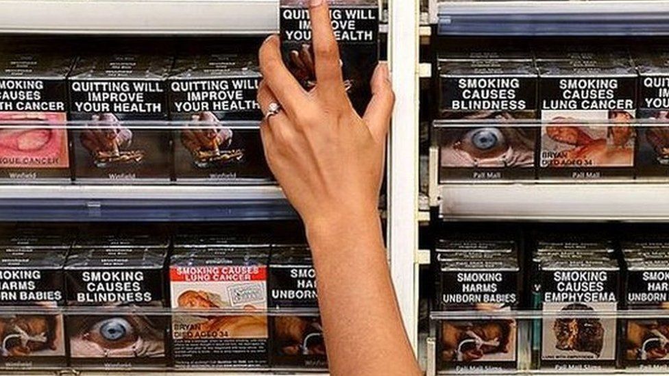 An employee in an Australia store selects a package of cigarettes
