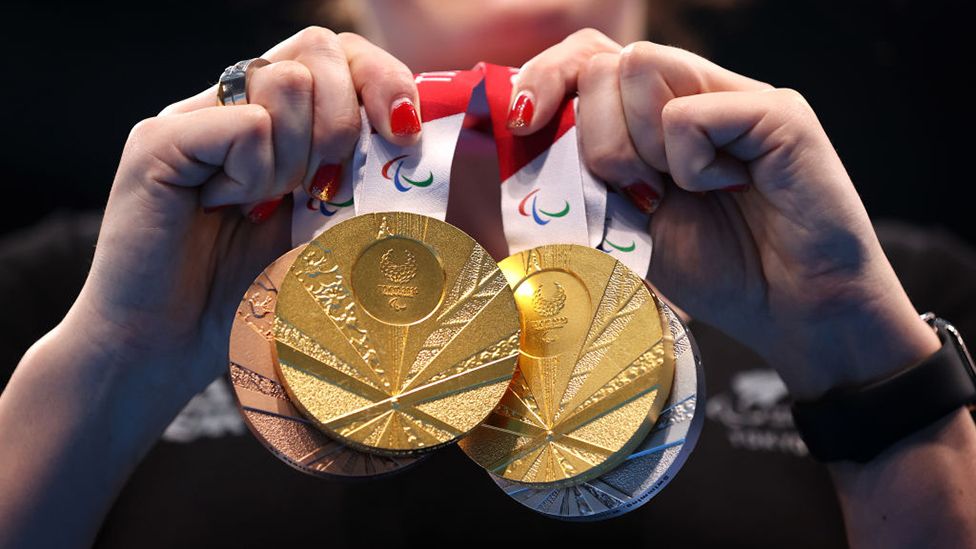 An athletes holds a clutch of Paralympic medals