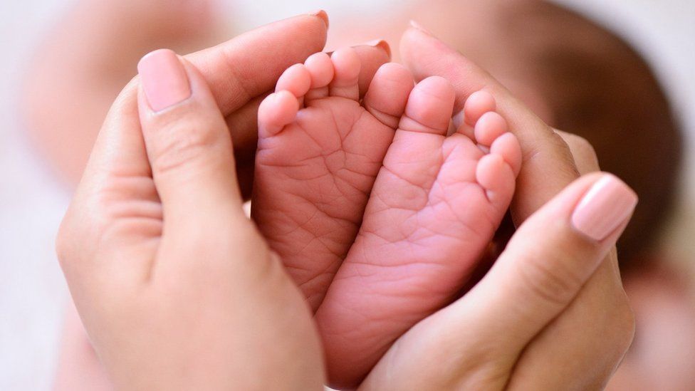 Baby's feet being held in adult hands