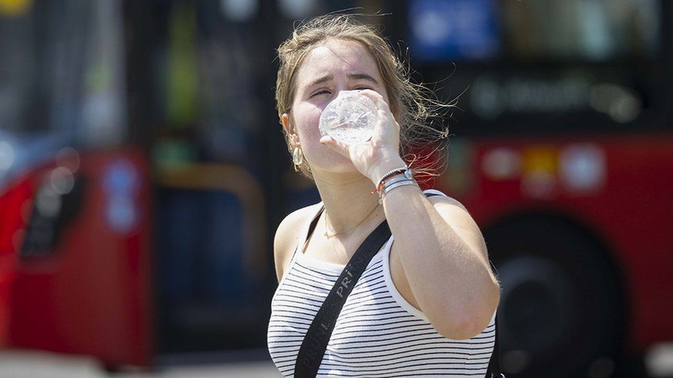 A women drinks water to cool off as heatwave hits London, 19 July 2022