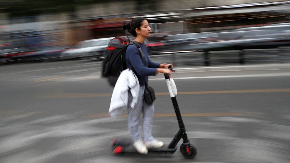 A woman rides a dock-free electric scooter in a Paris street in September 2019